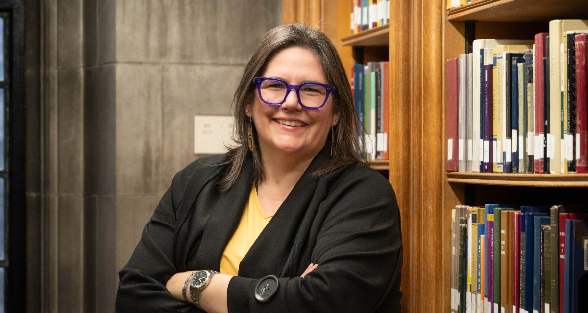 Carmen Lansdowne leaning against a bookshelf.