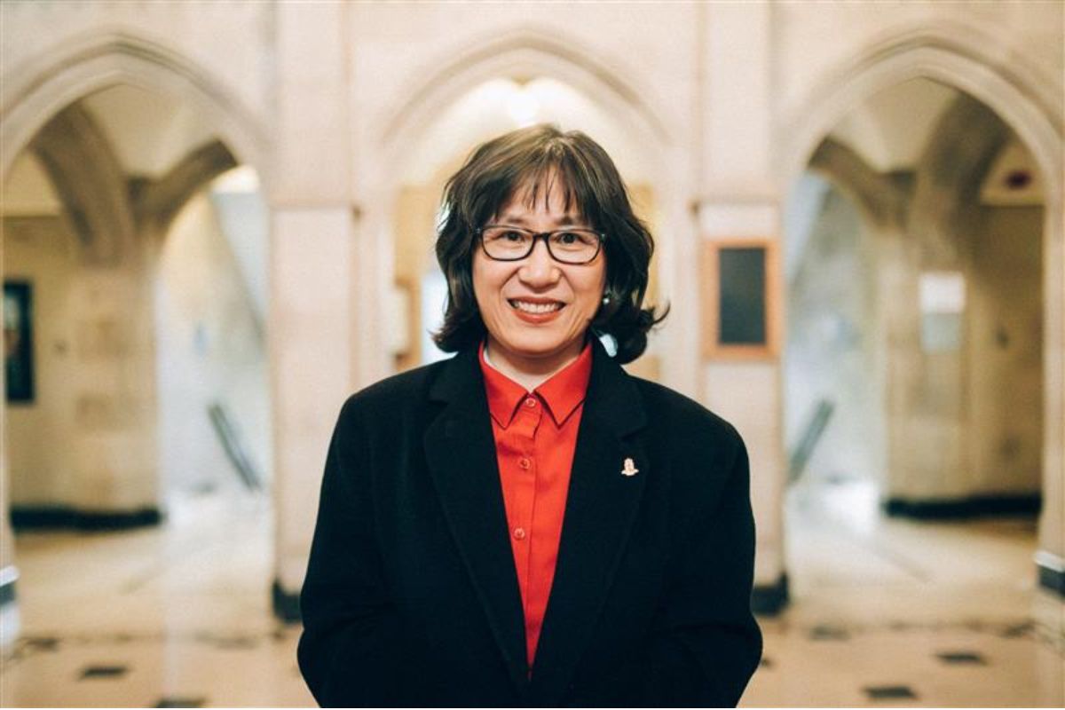 Principal HyeRan Kim-Cragg, smiling, stands inside Emmanuel College.